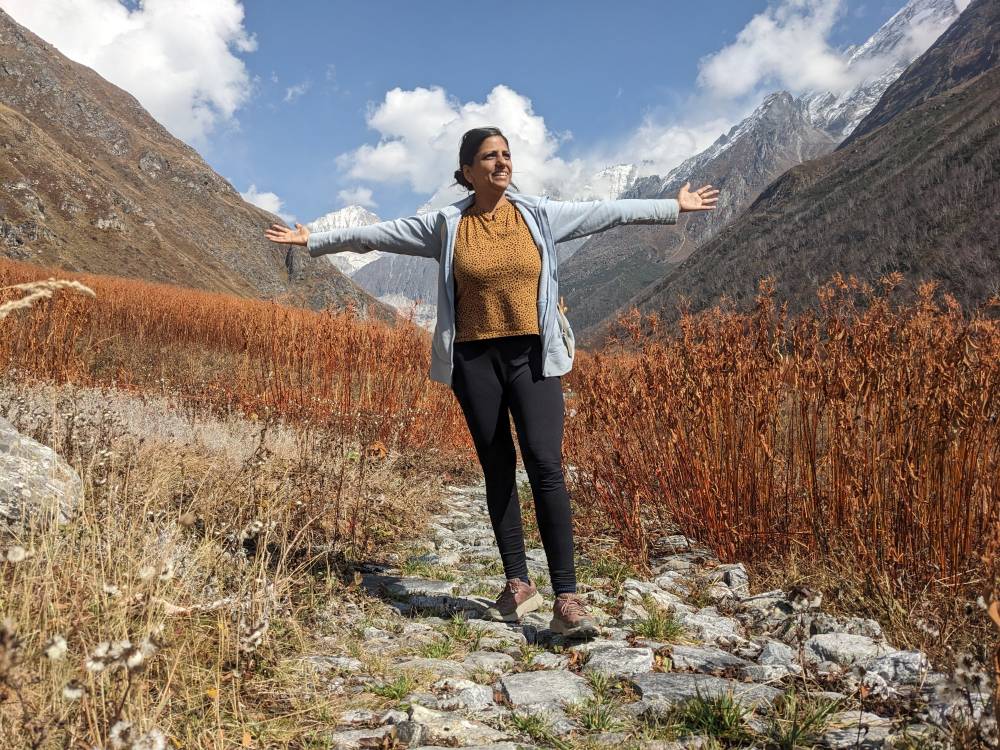 the author standing in beautiful mountains with arms open embracing her long writing and travel journey