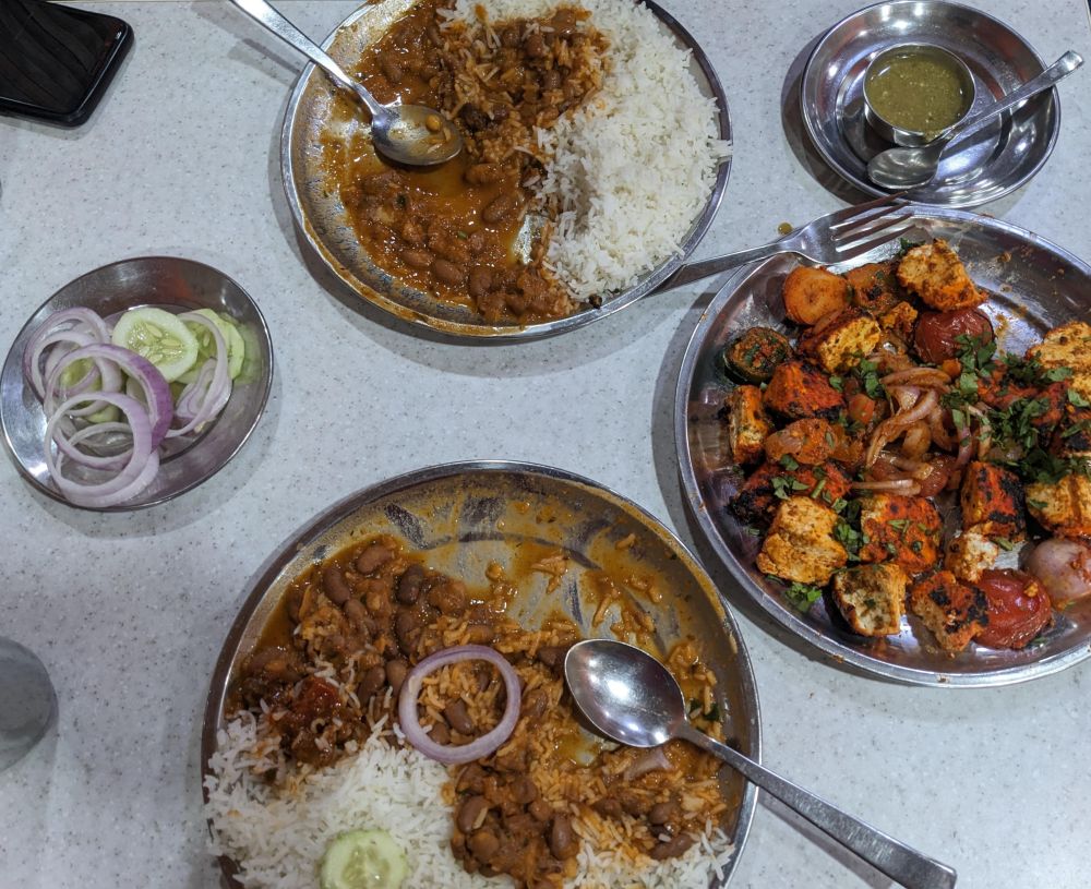 red kidney beans or rajma rice on plates along with grilled cottage cheese and onions